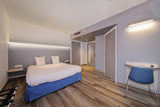 A modern hotel room with a double bed, wood floors, and minimalistic decor features sleek architectural lighting using the 1.3" Surface Mount Side-Lighting LED Channel (Model Vario30-03).