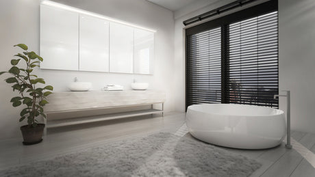 Modern bathroom with a large round white tub, double sinks on a floating vanity, and architectural lighting using the 1.3" Surface Mount Side-Lighting LED Channel (Model Vario30-03). Floor-to-ceiling windows with black blinds keep the space bright and minimalistic.