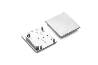 Two square metallic plates are shown on a white background: one is flat, and the other is an End Cap for Vario30-03 Profile, featuring four vertical pegs and engraved markings on its surface.