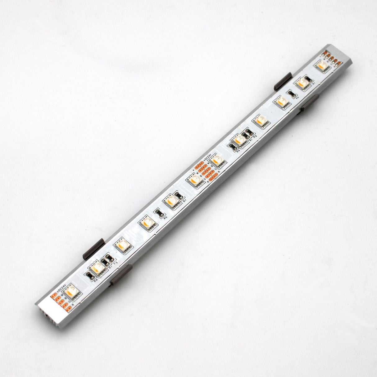 A silver Yukon LED profile light strip with multiple small LEDs on a metallic bar is mounted on a plain white background using the Surface Mount for Yukon Profile accessories.
