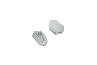 Two small white plastic C End Caps for Arc12 Duo Profile lighting fixture—each with angled sides—are shown on a plain white background; one end cap is facing up to display two pegs and a slot, while the other is facing down.