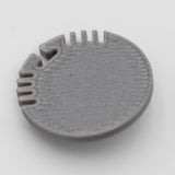A gray plastic End Cap for Alu Round Profile, round and flat with a textured surface and evenly spaced edge notches and grooves—perfect for finishing your profile—shown on a plain white background.