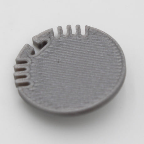 A gray plastic End Cap for Alu Round Profile, round and flat with a textured surface and evenly spaced edge notches and grooves—perfect for finishing your profile—shown on a plain white background.
