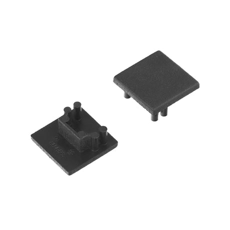 Two small, black End Caps for Cozy12 Profile are shown. One lies flat with three vertical pegs and a raised profile section; the other is upside-down, showing its flat surface and three short pegs for lighting fixture installation.