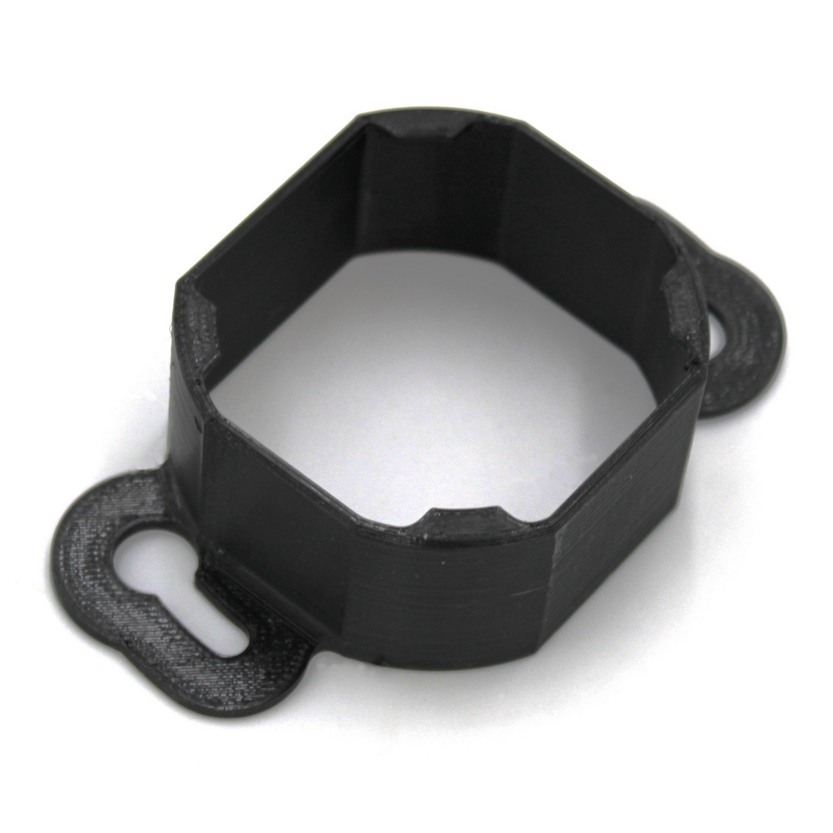 The Mounting Bracket for Casambi Smart Relay is a black, octagonal PETG bracket with two flat, rounded tabs featuring keyhole slots for secure mounting to surfaces. Ideal for use with the Casambi Smart Relay.