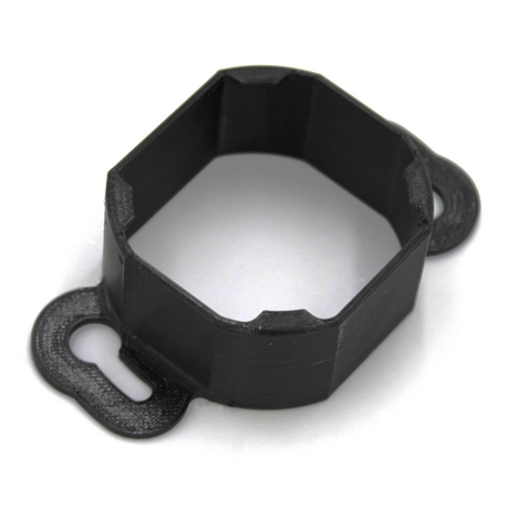 The Mounting Bracket for Casambi Smart Relay is a black, octagonal PETG bracket with two flat, rounded tabs featuring keyhole slots for secure mounting to surfaces. Ideal for use with the Casambi Smart Relay.