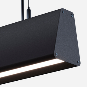 Close-up of the Suspended Linear Trapezoid LED Light Fixture ~ Model Dalia, a modern black rectangular pendant with a glowing lower edge, hanging by two cables against a plain white background.