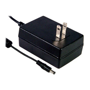 The Meanwell GST Series Plug-type Power Supply (24V) is a black, energy-efficient adapter with two prongs and a barrel jack connector, ideal as a wall-mounted power supply for various devices. Set against a white background.