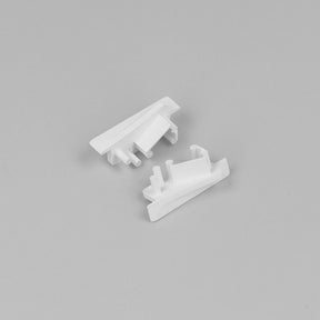 Two small, white End Caps for Diagonal10 Profile, featuring angular shapes and protruding pegs, are displayed on a plain light gray background.