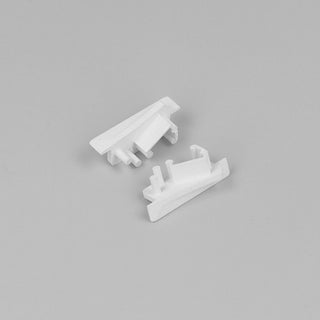 Two small, white End Caps for Diagonal10 Profile, featuring angular shapes and protruding pegs, are displayed on a plain light gray background.