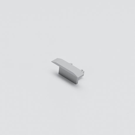 A single light gray Cut & Connect End Cap for Berlin Profile, resembling a LEGO piece, sits centered on a plain white background. Its sloped design and smooth top evoke the clean finish of an IP65 seal.