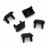 Five small, black plastic Cut & Connect End Caps for Roma Profile, each with prongs and a rectangular shape, are arranged on a white surface. Designed to securely cover the ends of open tubes or rectangular sections, these end caps provide an IP65 seal—ideal for protecting connections in linear lighting systems.