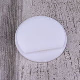 A round, flat Plastic End Cap for Cascade38 Profile with a shallow groove rests on a textured, light-colored wooden surface.
