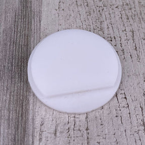 A round, flat Plastic End Cap for Cascade38 Profile with a shallow groove rests on a textured, light-colored wooden surface.