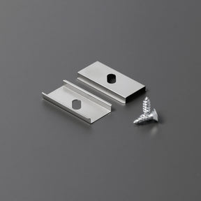 Two Mounting Clip U1 aluminum clips with oval holes and two silver screws are arranged on a gray surface, designed for secure installation with the Cozy12 profile.