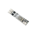 A close-up of the Compact In-channel Casambi Bluetooth Controller, a rectangular circuit board featuring chips, connectors, and RGB LEDs, set against a solid black background.