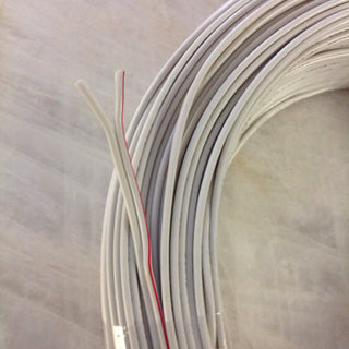 A coiled bundle of 2-Core 18 AWG PVC Flat Ribbon Wire for Single Color LED Strip and Power lies on a light surface, showing two ends—one with a red stripe, one all white—perfect for LED installation projects.